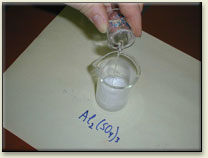 The solution of sodium carbonate is poured into the solution of aluminum sulfate